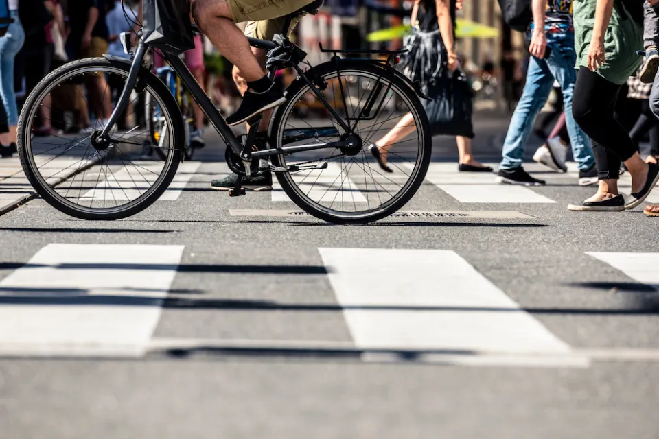 Low shot of pedestrians and a bike crossing a striped crosswalk.